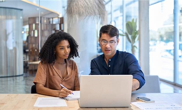 woman and man at desk in front of a laptop